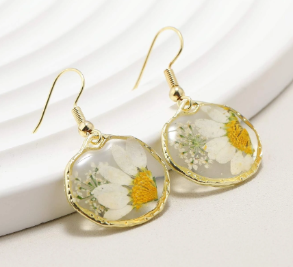 White daisies adorn earrings made of resin in Neemaflowers' botanic jewelry collection.